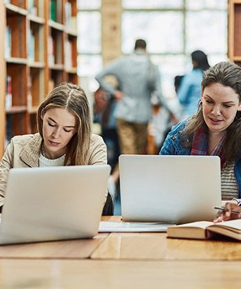studenti pracují na laptopech v knihovně