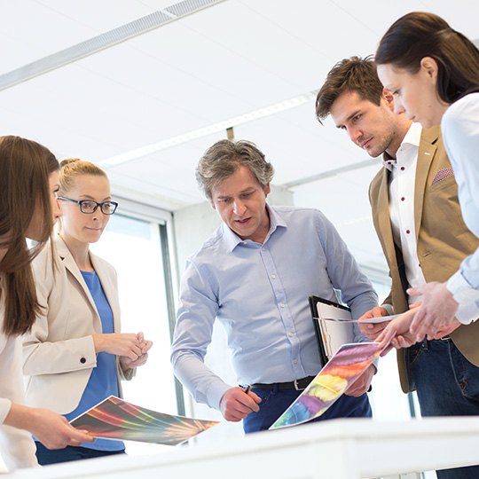 kolegové nad stolem s výtisky