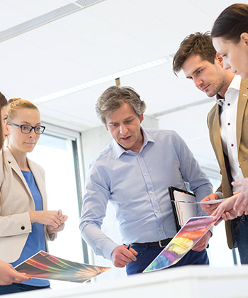 kolegové nad stolem s výtisky